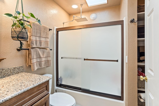 full bathroom featuring toilet, bath / shower combo with glass door, and vanity