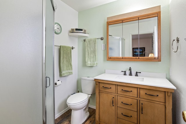 bathroom featuring toilet, a shower with door, hardwood / wood-style floors, and vanity