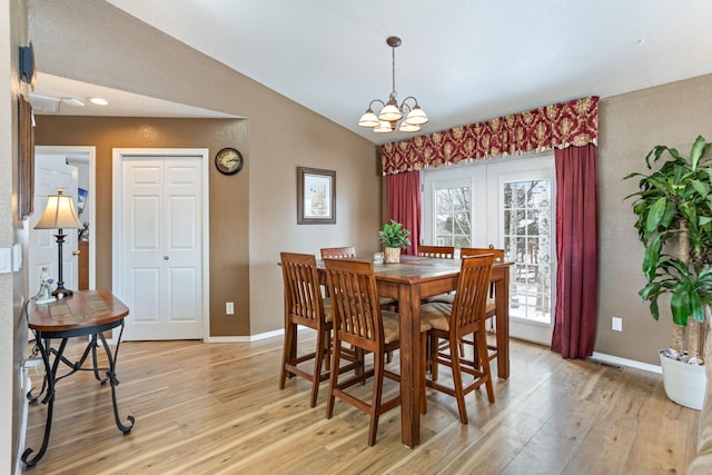 dining space featuring an inviting chandelier, vaulted ceiling, and light hardwood / wood-style flooring