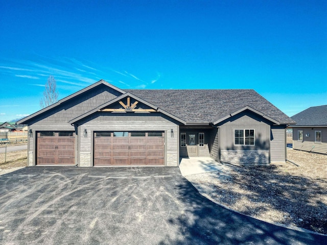 view of front facade featuring stone siding, an attached garage, and driveway