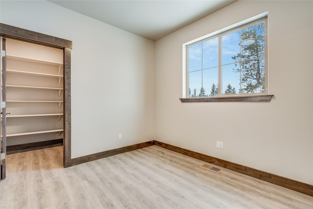 unfurnished bedroom featuring a walk in closet and light hardwood / wood-style flooring