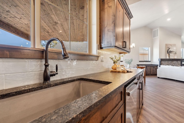 kitchen featuring visible vents, a sink, tasteful backsplash, lofted ceiling, and dishwasher