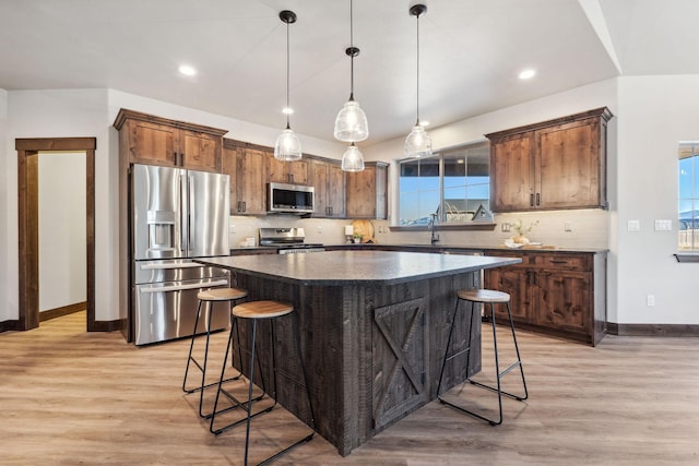 kitchen with a kitchen bar, light wood-type flooring, a sink, a kitchen island, and stainless steel appliances