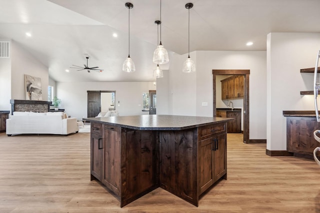 kitchen featuring dark countertops, dark brown cabinets, light wood finished floors, and a center island