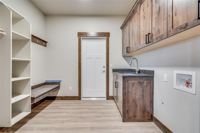 clothes washing area featuring wood finished floors, hookup for a washing machine, cabinet space, and a sink