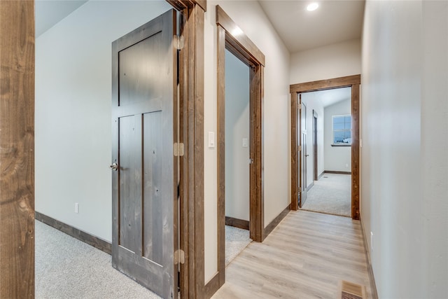 corridor with light wood-style floors, baseboards, and visible vents