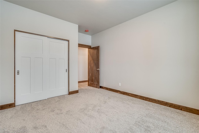 unfurnished bedroom with a closet, baseboards, and carpet flooring