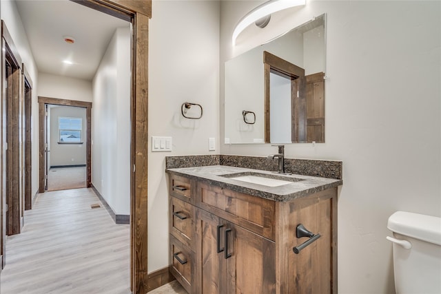 bathroom featuring toilet, hardwood / wood-style floors, and vanity