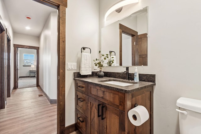 bathroom with vanity, toilet, wood finished floors, and baseboards