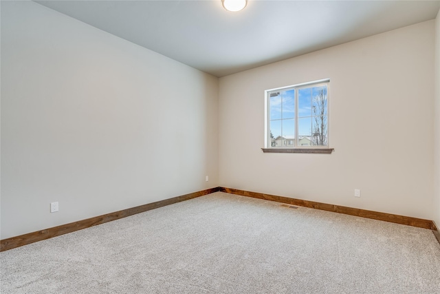 empty room featuring carpet flooring, visible vents, and baseboards