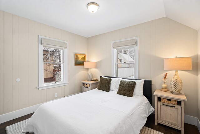 bedroom with lofted ceiling, multiple windows, and dark wood-style floors