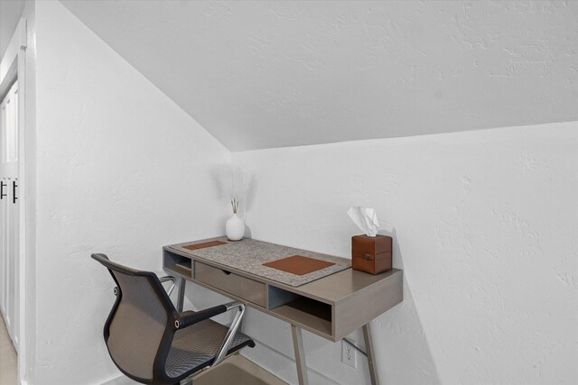 office area with a textured wall, a textured ceiling, and vaulted ceiling