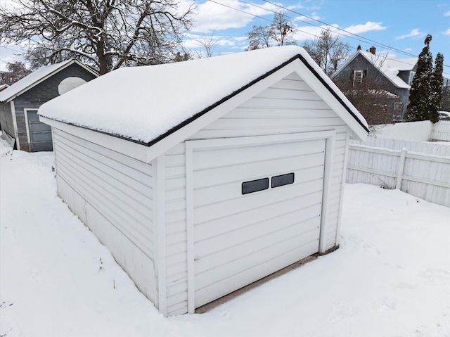 snow covered structure with an outbuilding and fence