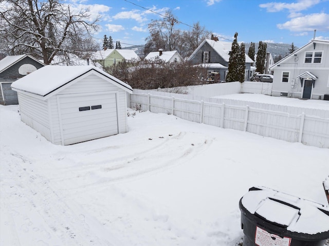 yard layered in snow with a residential view, a storage shed, an outdoor structure, and fence