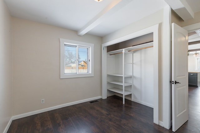 unfurnished bedroom with beam ceiling, a closet, and dark hardwood / wood-style floors