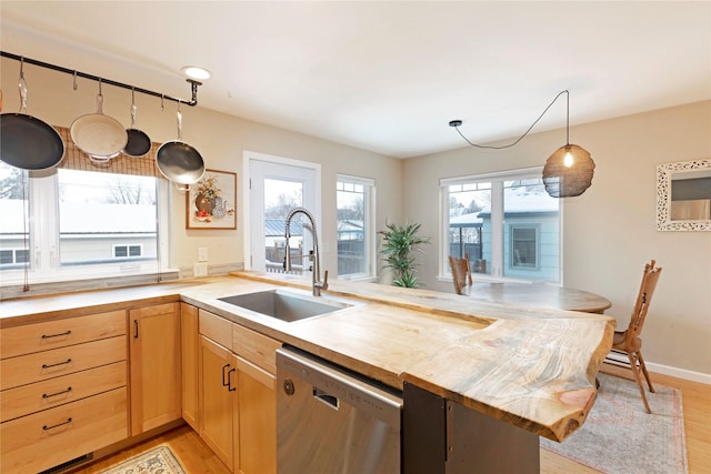 kitchen featuring dishwasher, kitchen peninsula, pendant lighting, sink, and light hardwood / wood-style flooring