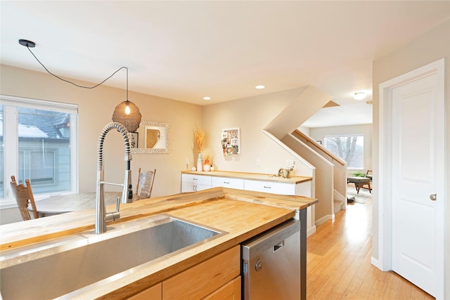 kitchen featuring sink, dishwasher, light hardwood / wood-style floors, butcher block countertops, and pendant lighting