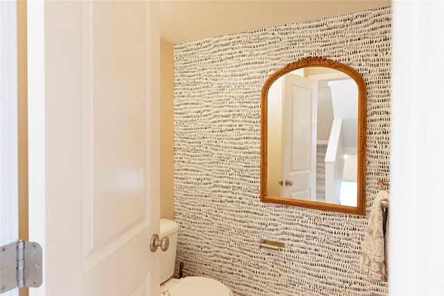 bathroom featuring brick wall and toilet