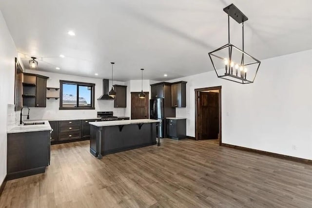 kitchen featuring refrigerator, decorative light fixtures, sink, a center island, and wall chimney range hood