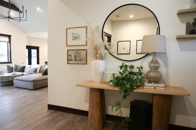 hallway with vaulted ceiling, dark hardwood / wood-style floors, and a notable chandelier