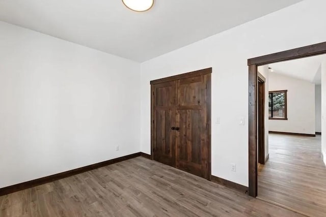 unfurnished bedroom featuring dark wood-type flooring and vaulted ceiling