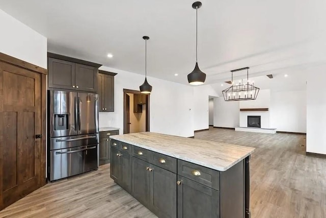 kitchen featuring pendant lighting, light hardwood / wood-style flooring, a center island, light stone countertops, and stainless steel fridge with ice dispenser