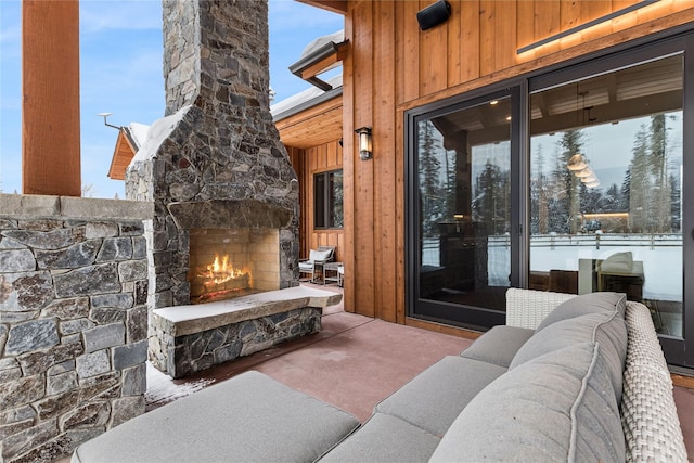 snow covered patio featuring an outdoor stone fireplace