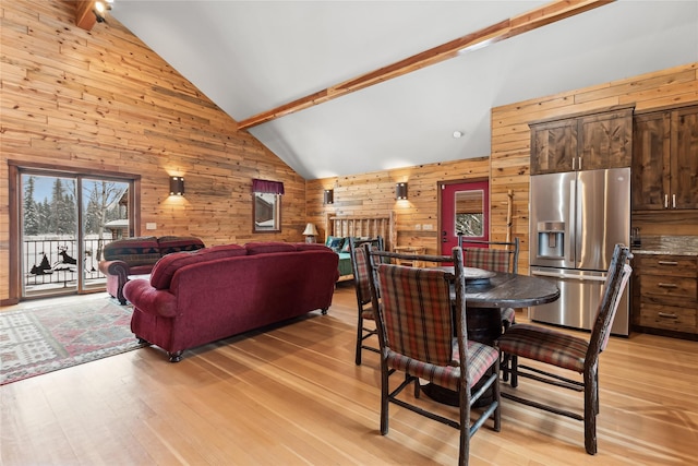 dining room with wooden walls, ceiling fan, high vaulted ceiling, light hardwood / wood-style flooring, and beamed ceiling