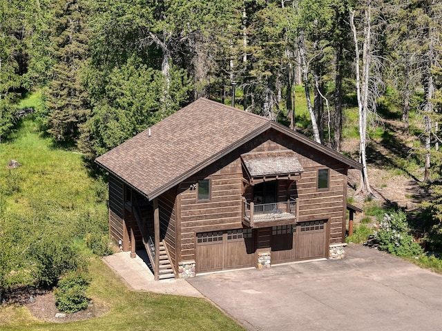 190 Black Bear Ln, Bigfork, MT 59911 - chalet / cabin featuring driveway, stairs, a shingled roof, a garage, and a balcony