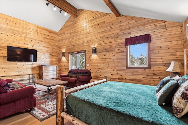 bedroom featuring beamed ceiling, wooden walls, track lighting, and hardwood / wood-style floors