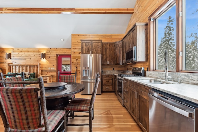 190 Black Bear Ln, Bigfork, MT 59911 - kitchen featuring stainless steel appliances, wood walls, light wood-type flooring, a sink, and dark brown cabinetry