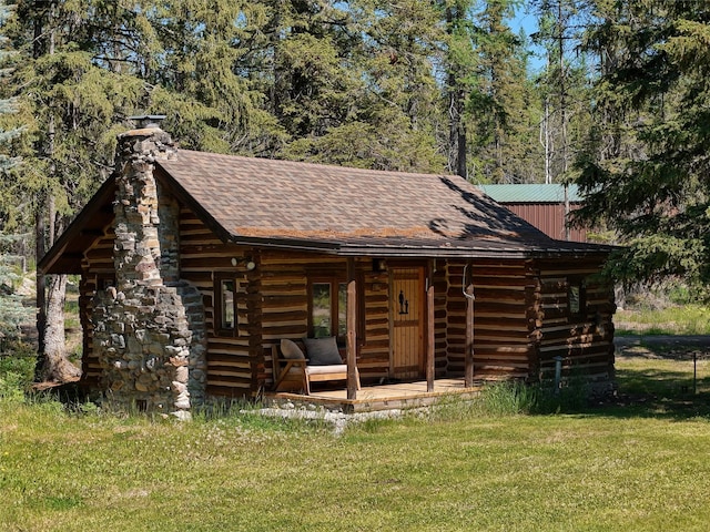 190 Black Bear Ln, Bigfork, MT 59911 - view of front of house featuring a chimney, log siding, a front lawn, and roof with shingles