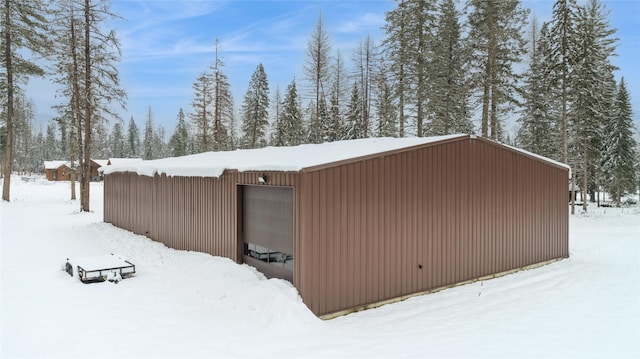 snow covered structure featuring a garage