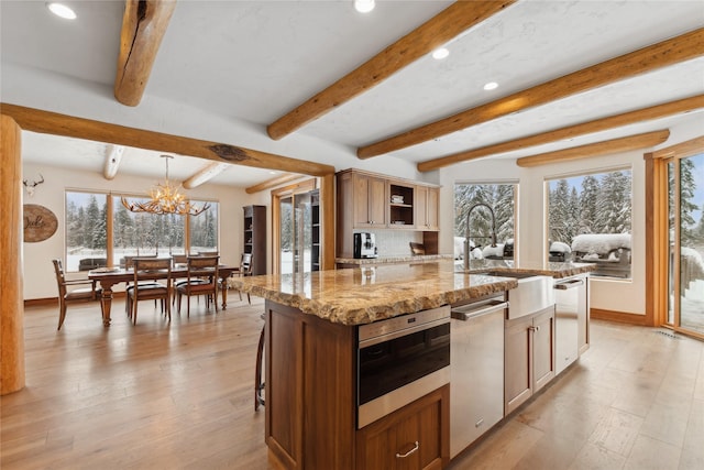 kitchen featuring a center island, hanging light fixtures, light stone countertops, a chandelier, and sink