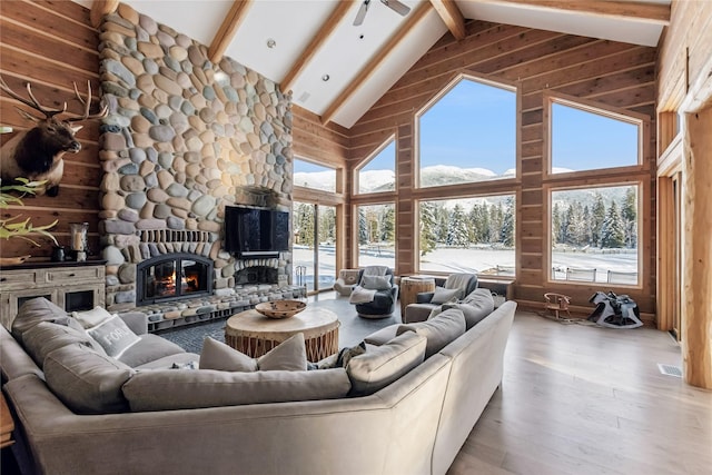 190 Black Bear Ln, Bigfork, MT 59911 - living room with high vaulted ceiling, beamed ceiling, wood finished floors, a stone fireplace, and wooden walls