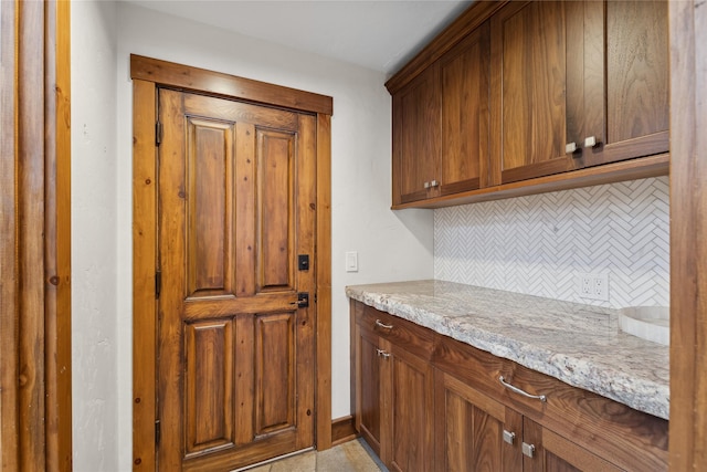 kitchen featuring tasteful backsplash, light tile patterned flooring, and light stone counters