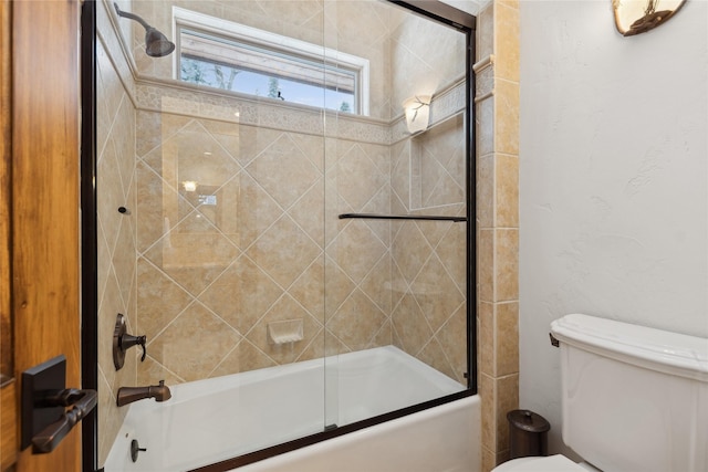 bathroom with toilet and shower / bath combination with glass door