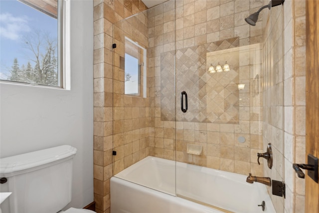 bathroom with toilet and bath / shower combo with glass door