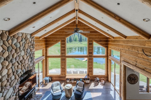 190 Black Bear Ln, Bigfork, MT 59911 - unfurnished living room with ceiling fan, wood finished floors, a stone fireplace, wood walls, and a water view