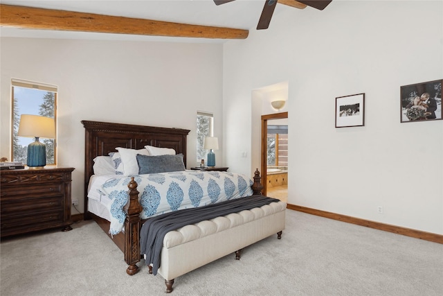 bedroom with light carpet, ceiling fan, beamed ceiling, and ensuite bath