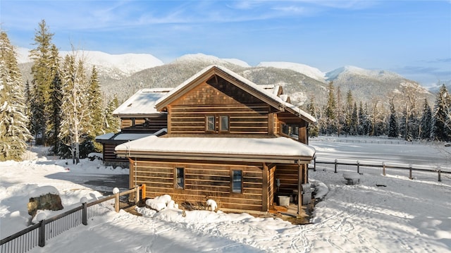 snow covered back of property featuring a mountain view