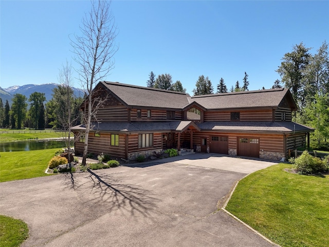 190 Black Bear Ln, Bigfork, MT 59911 - log cabin featuring driveway, a front yard, a water and mountain view, and a shingled roof