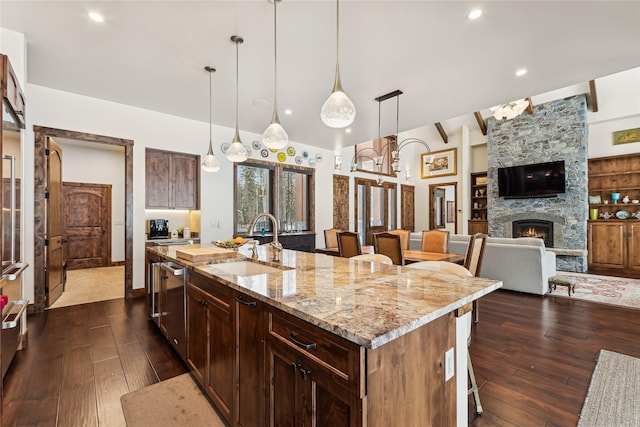 190 Black Bear Ln, Bigfork, MT 59911 - kitchen featuring a sink, dishwasher, dark wood-style floors, a fireplace, and an island with sink