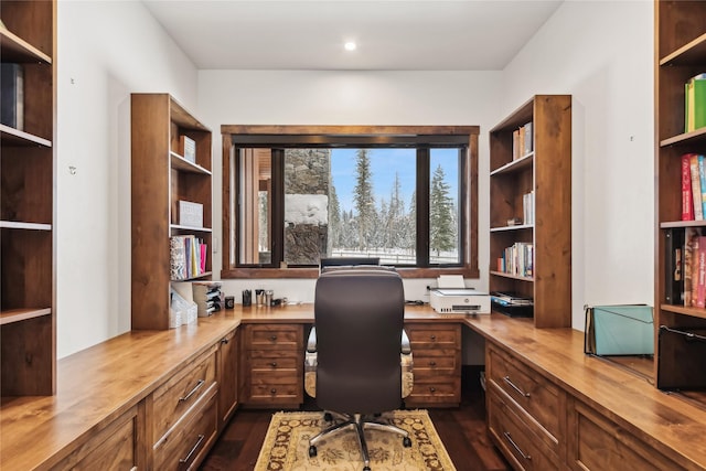 home office featuring dark hardwood / wood-style floors and built in desk