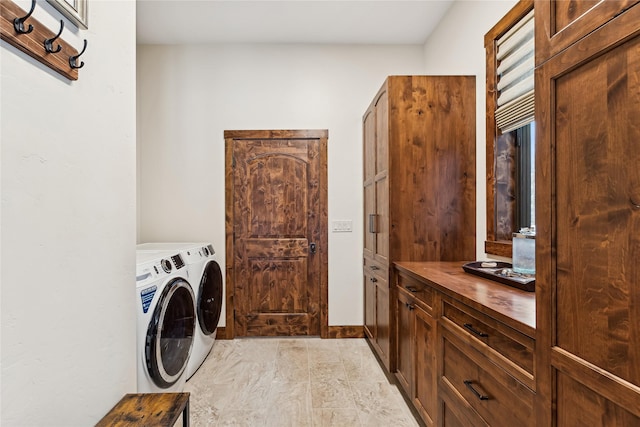 clothes washing area with cabinets and independent washer and dryer