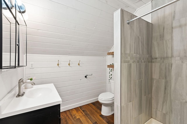 bathroom featuring hardwood / wood-style floors, toilet, tiled shower, and vanity