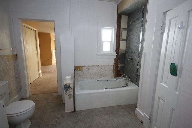 bathroom with a washtub, tile patterned flooring, and toilet