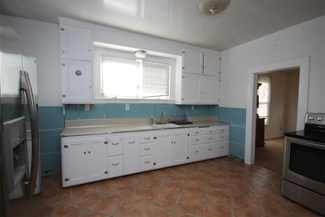 kitchen featuring a sink, appliances with stainless steel finishes, white cabinets, and light countertops