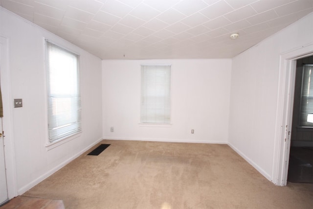 spare room with carpet flooring, baseboards, and visible vents