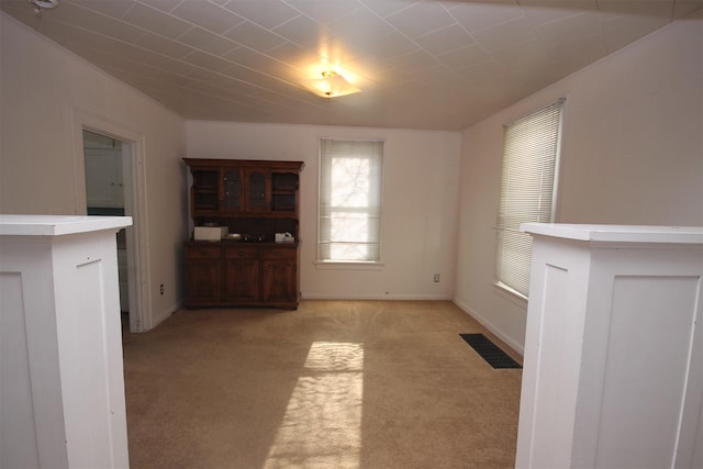 unfurnished dining area with visible vents, baseboards, and light colored carpet